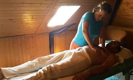 Une masseuse appuie des deux mains sur le torse d'un homme allongé sur le dos, sous une fenêtre de toit