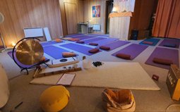 La salle préparée pour une séance : tapis, coussins et un gong posés au sol